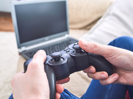 man holding a joystick controllers while playing a video games at home
