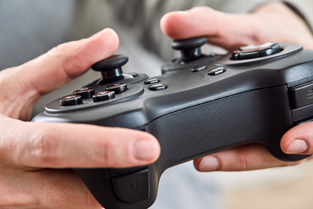 man holding a joystick controllers while playing a video games at home