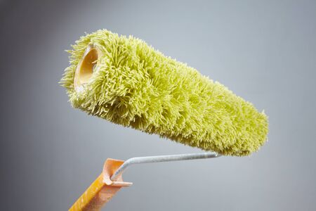 Hands holding paint roller rolling paint on a wallの写真素材