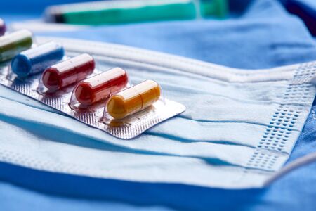 Pharmaceutical medicine tablets, pills, capsules and medical mask on blue background. Medicine concept. Coronavirusの写真素材