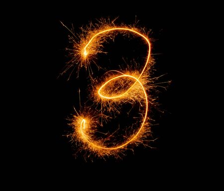 number three written with a sparkler on a black backgroundの写真素材