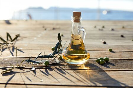 Olive oil in the bottle and branch of green olivesの写真素材