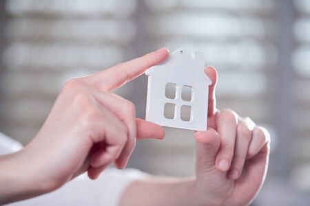 Female hands holding model of house