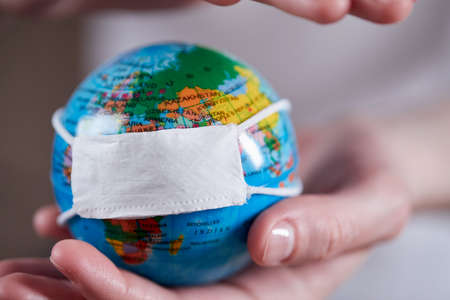 woman holding globe with protective maskの写真素材