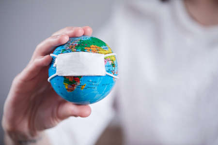 woman holding globe with protective maskの写真素材