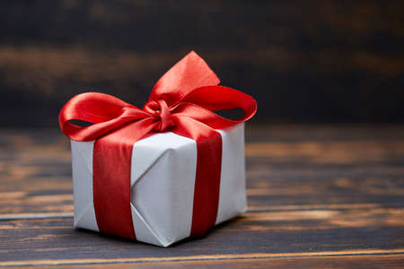 A gift tied with a red ribbon. On a wooden table.の写真素材