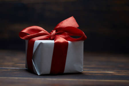 A gift tied with a red ribbon. On a wooden table.の写真素材