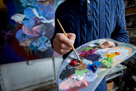 Adult man painter painting on canvas backgroundの写真素材