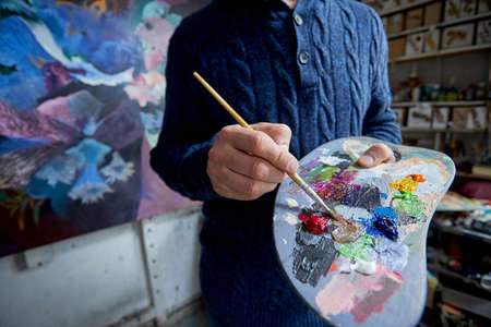 Adult man painter painting on canvas backgroundの写真素材
