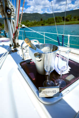 Romantic luxury evening on cruise yacht with champagne setting. Empty glasses and bottle with champagne and tropical sunset with sea backgroundの写真素材