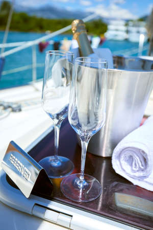 Romantic luxury evening on cruise yacht with champagne setting. Empty glasses and bottle with champagne and tropical sunset with sea backgroundの写真素材