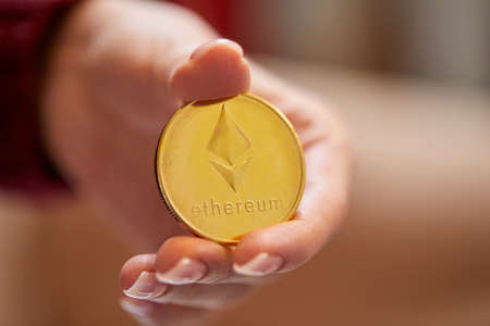 Hand holding golden bitcoin ethereumの写真素材