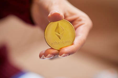 Hand holding golden bitcoin ethereumの写真素材