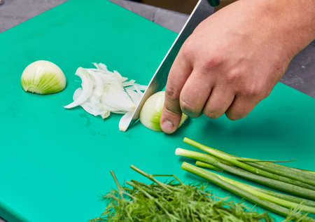 chef cutting onion on the kitchenの写真素材