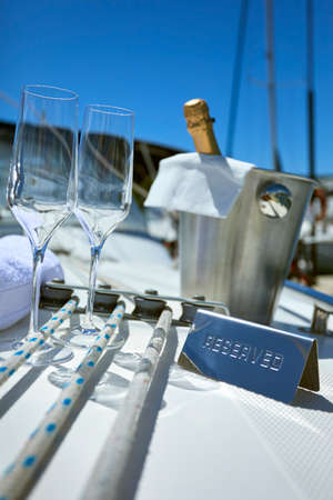 Romantic luxury evening on cruise yacht with champagne setting. Empty glasses and bottle with champagne and tropical sunset with sea backgroundの写真素材
