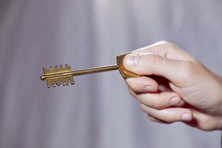 Close up of human hand holding golden keyの写真素材