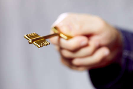 Close up of human hand holding golden keyの写真素材