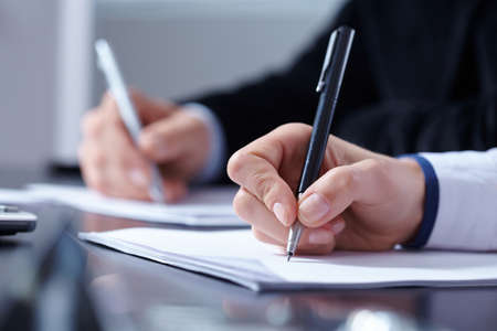 man and woman hands signing contract paper in officeの写真素材