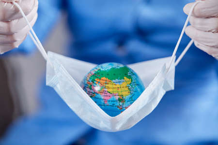 scientist holding globe in protective maskの写真素材