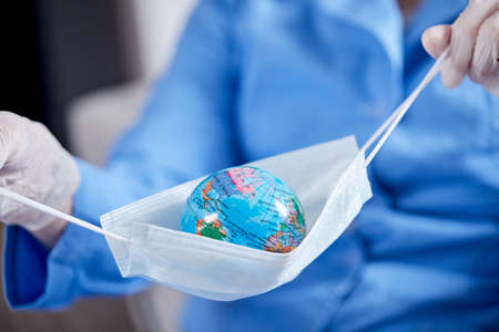 scientist holding globe in protective maskの写真素材