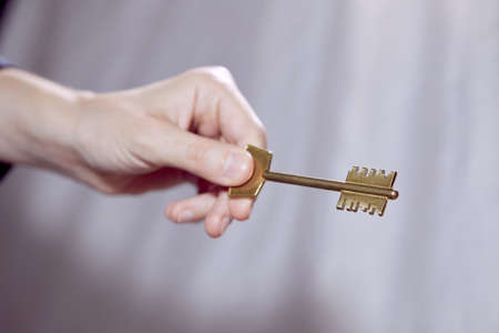 Close up of human hand holding golden keyの写真素材