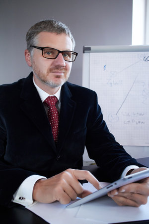 businessman sitting in office working on tabletの写真素材