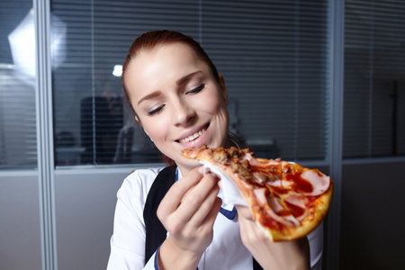 businesswomen with pizza in officeの写真素材