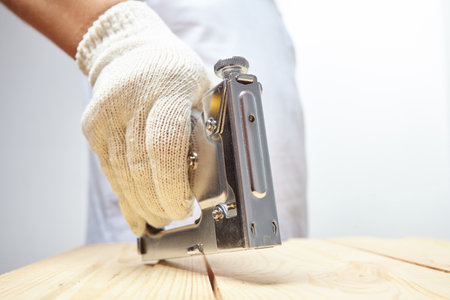 Male installer using stapler for wooden plankの写真素材