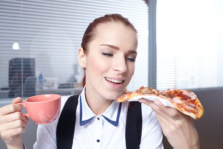 businesswomen with pizza in officeの写真素材