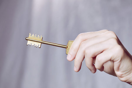 Close up of human hand holding golden keyの写真素材