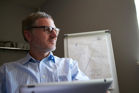 Middle age man working in home office with pc tabletの写真素材