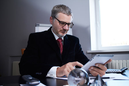 Middle age man working in home office with pc tabletの写真素材