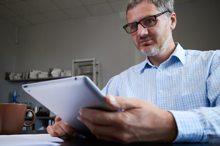 Middle age man working in home office with pc tabletの写真素材