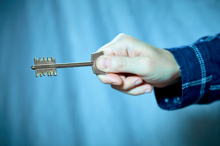 Close up of human hand holding golden keyの写真素材