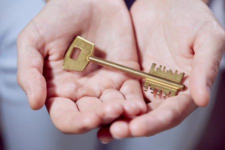 Close up of human hand holding golden keyの写真素材