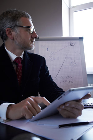 Middle age man working in home office with pc tabletの写真素材