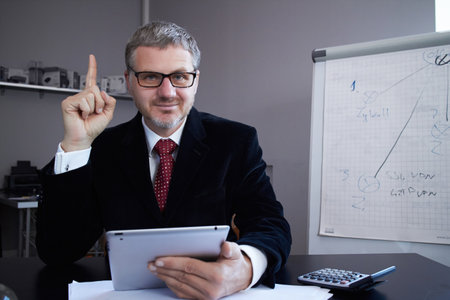 Middle age man working in home office with pc tabletの写真素材