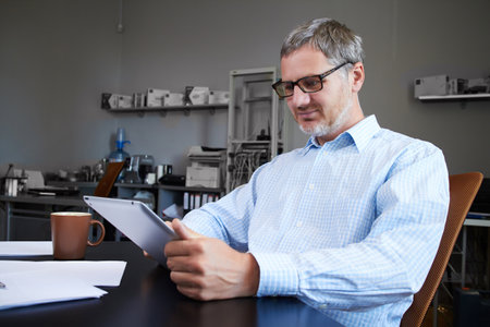 Middle age man working in home office with pc tabletの写真素材