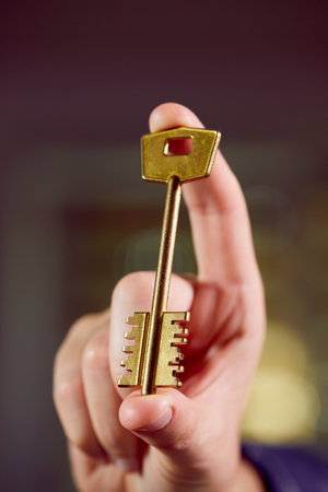 Close up of human hand holding golden keyの写真素材