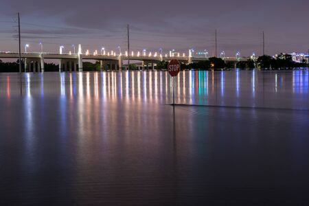 Night photo of a stop sign in the flood waters of the Trinity River with the lights of the Hampton Street Bridge in Dallas Texas in the background. May 31 2015 Photography by Stretchの写真素材