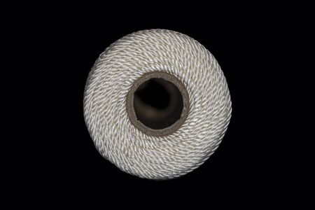 Closeup of the end of white string twine wrapped around a cardboard tube against a black backgroundの写真素材