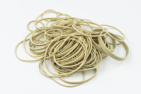 A stack of different sized latex, rubber bands on a white background ready for assorted uses in school, an office, or miscellaneous other environments.の写真素材