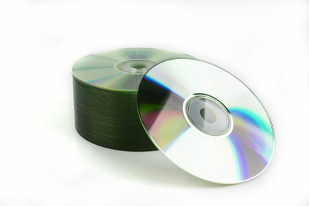A stack of CD or DVD storage media discs neatly stacked with one disc offset and leaning on the...