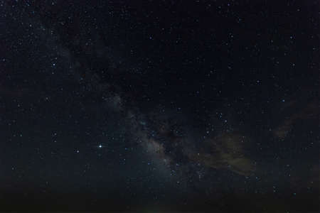 Heart of the Milky Way in a night sky full of stars with some light, wispy clouds passing by overhead.の写真素材