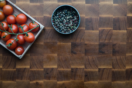 cherry tomatoes and pepper on a wooden brown handmade cutting boardの写真素材
