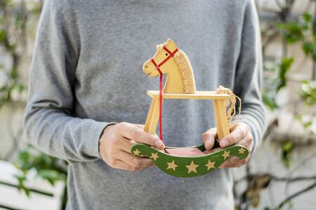 An adult man holding his old toys, no recognizable face, with a neutral background.の写真素材
