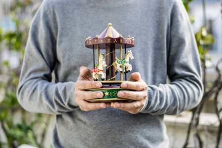 An adult man holding his old toys, no recognizable face, with a neutral background.の写真素材