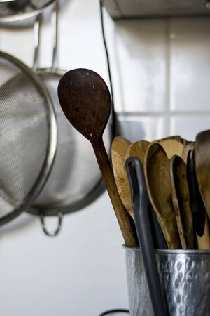 Old wooden kitchen utensils in a metal bowl in a white kitchenの写真素材