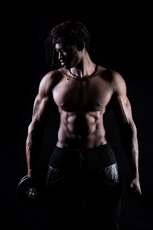 Afro american showing muscles in studio with a black backgroundの写真素材