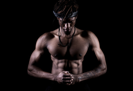 Afro american model showing muscles in studio with a black backgroundの写真素材